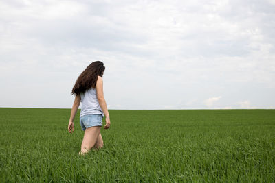 Full length of young woman standing on agricultural field against sky