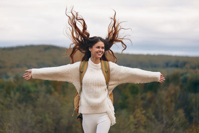 Young woman standing against sky