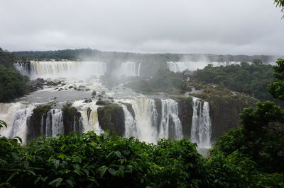 Scenic view of waterfall in forest against sky