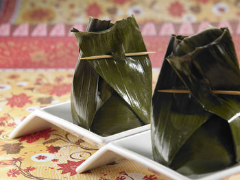 Close-up of food wrapped in banana leaves served in plate on table