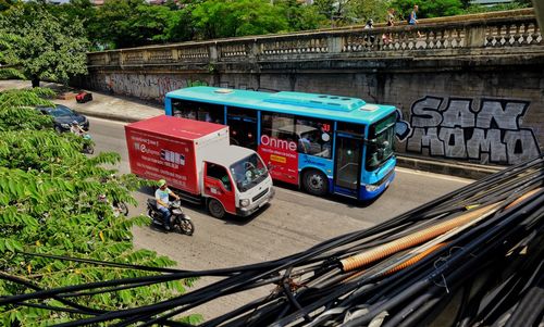 Vehicles on road against plants in city