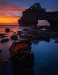 Rock formation on sea against sky during sunset