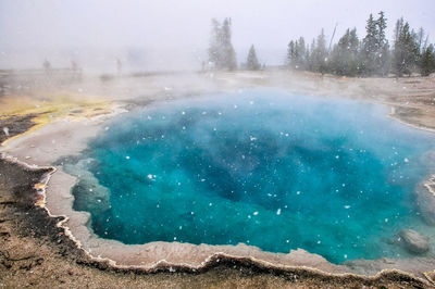 Snowflakes over black pool at west thumb in yellowstone national park.