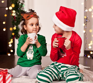 Portrait of siblings sitting on sofa at home