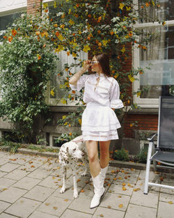 Rear view of young woman with dog standing against trees