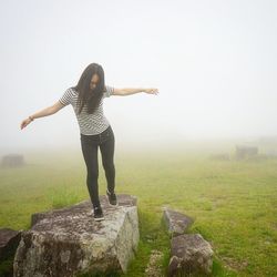 Woman with arms outstretched on landscape against sky