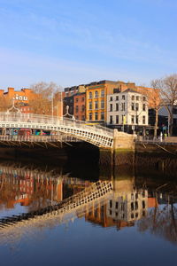 Bridge over river by buildings against sky in city