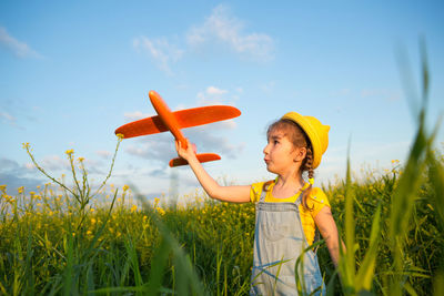 Cute girl standing on field against sky