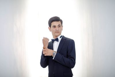 Portrait of young man standing against white background