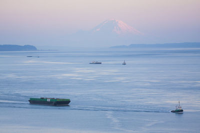 Tugboats pull barges in puget sound below mount rainier, washington