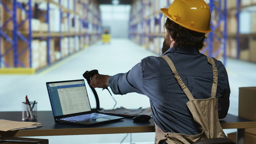 Rear view of man using laptop at office