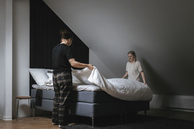 Women making bed together in morning