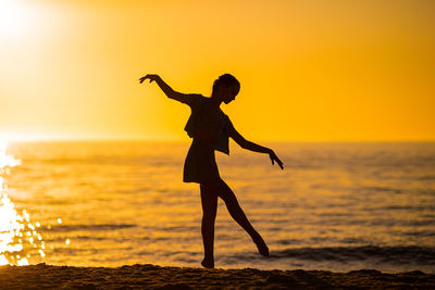 Silhouette woman standing at beach during sunset