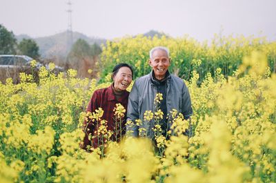 Smiling couple standing amidst flowering yellow plants