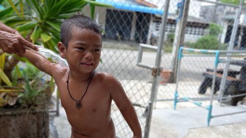 Portrait of shirtless boy standing outdoors