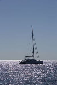 Sailboat sailing in sea against clear sky