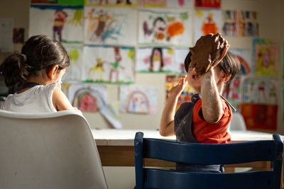 Little girl is showing the dough she prepared sitting on the chair