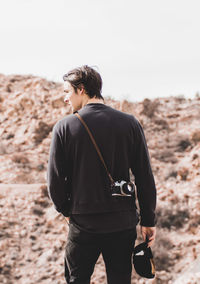 Rear view of man standing on beach against sky