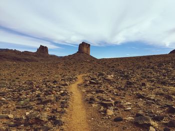 Rock formations in desert against cloudy sky