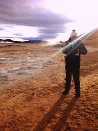 People standing on field against cloudy sky