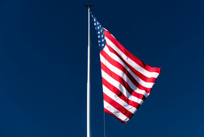 Low angle view of flags flag against clear blue sky