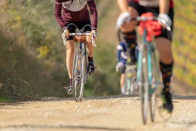 Low section of man riding bicycle on road