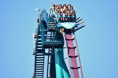 Low angle view of ferris wheel against clear blue sky