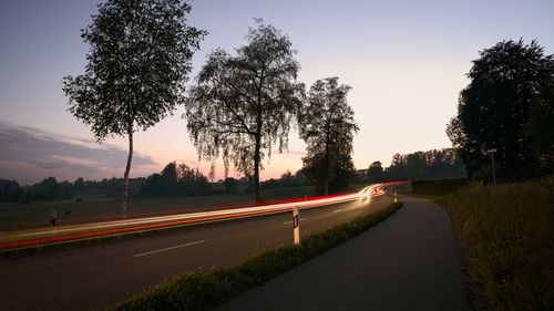 Light trails on street against sky at sunset