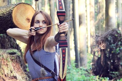 Young woman holding camera in forest