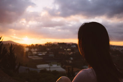 Silhouette of woman against cloudy sky at sunset