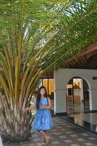 Woman standing by palm tree