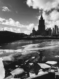 View of river and buildings against cloudy sky
