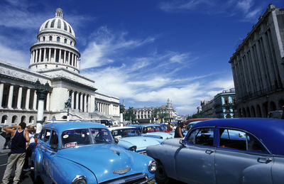 Vintage cars on street by historic building against sky