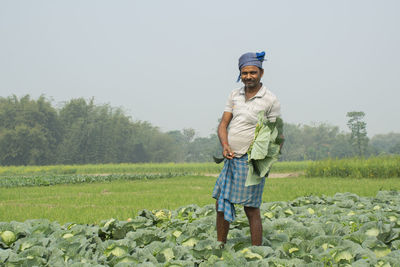 Full length of man standing on field holding vegetable