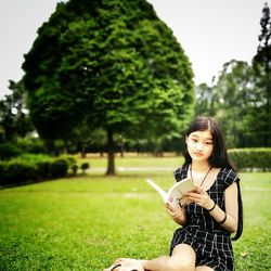 Portrait of smiling young woman using smart phone in park