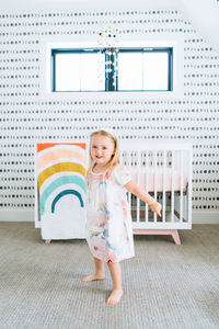 Straight on portrait of a toddler girl dancing in a modern nursery