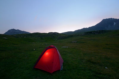 Tent in field against sky during sunset