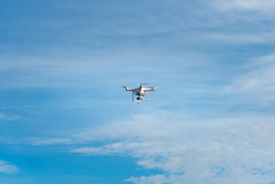 Low angle view of drone flying against blue sky during sunny day