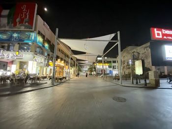 Illuminated street amidst buildings in city at night