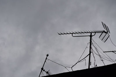 Low angle view of silhouette telephone pole against sky