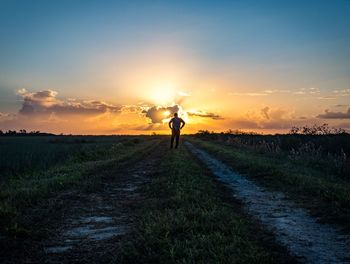 Silhouette man on field against sky during sunset