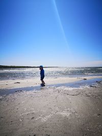 Man on beach against clear blue sky
