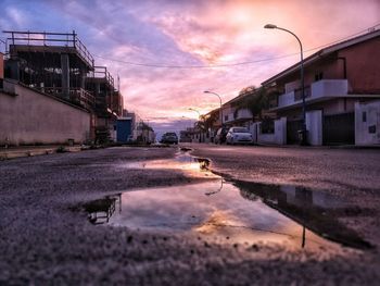 Surface level of wet street in city against sky