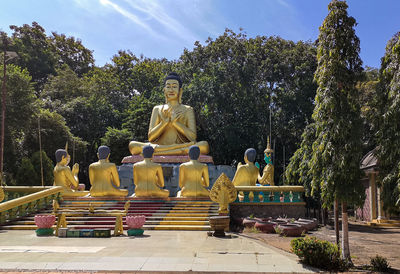 Statue against trees and temple against sky