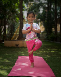 Portrait of cute girl doing yoga on grass