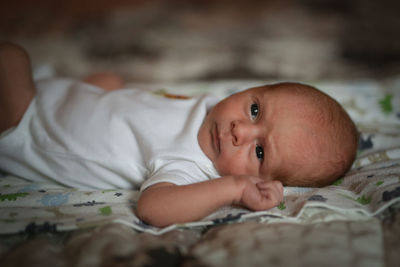 Close-up of cute baby boy  on bed at home