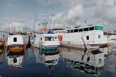 Boats moored at harbor against sky