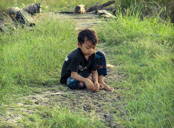 Portrait of boy sitting on grassy field