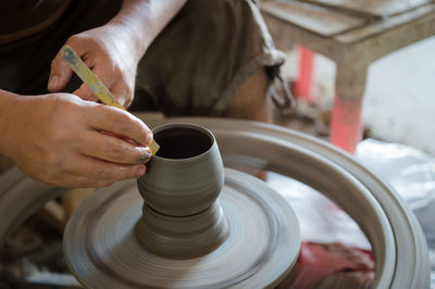 Midsection of man making clay pot