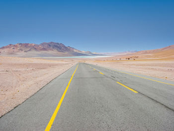 Road from chile towards bolivia. blue lake in the distance. no traffic.